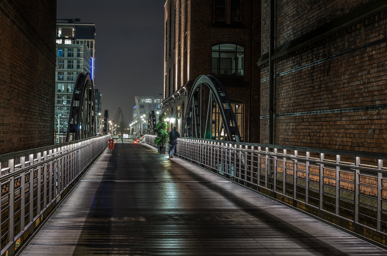 Person Standing Beside Gray Concrete Bridge Near Building